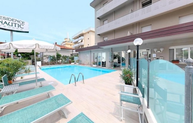 Piscina esterna con lettini e ombrelloni di un residence.