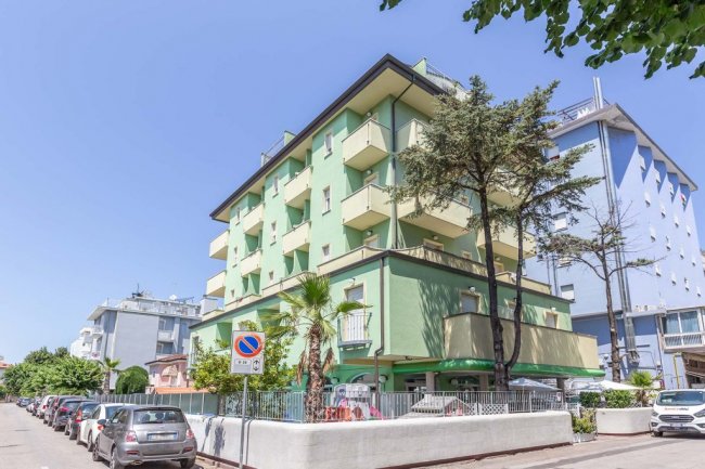 Edificio residenziale verde con diversi balconi.