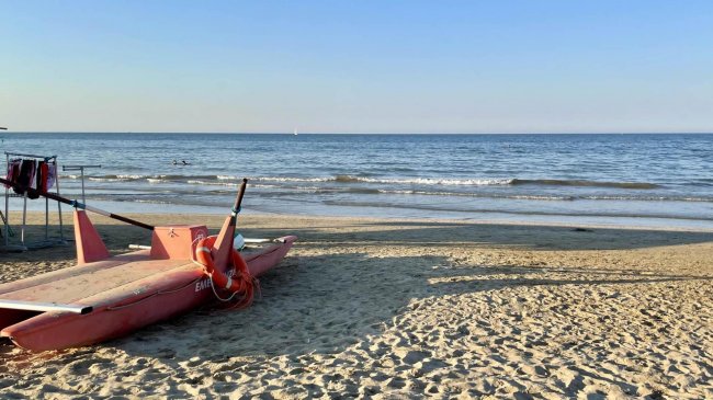 Una spiaggia con un pattino rosa sulla sabbia.