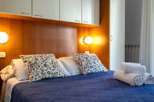 Camera da letto con copriletto blu e cuscini decorati.