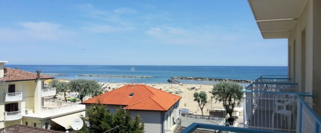 Vista mare da un balcone con spiaggia e case.