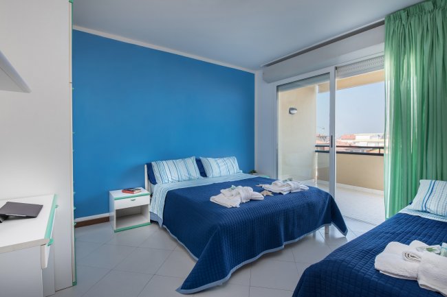 Camera da letto con parete blu e letti rifatti.