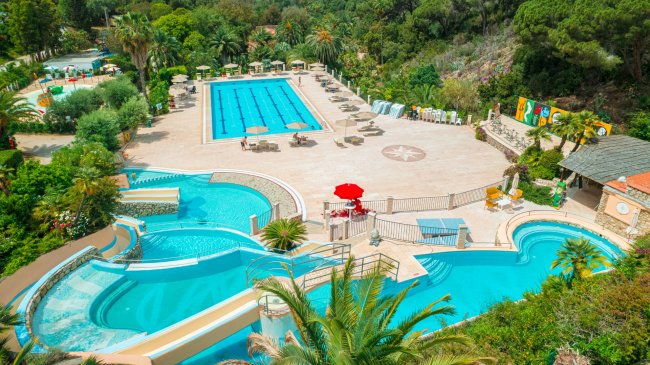 Complesso piscine con lettini e ombrelloni.