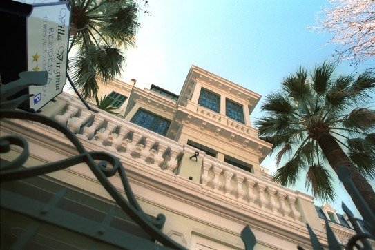 Edificio storico visto dal basso con palme e cielo azzurro.