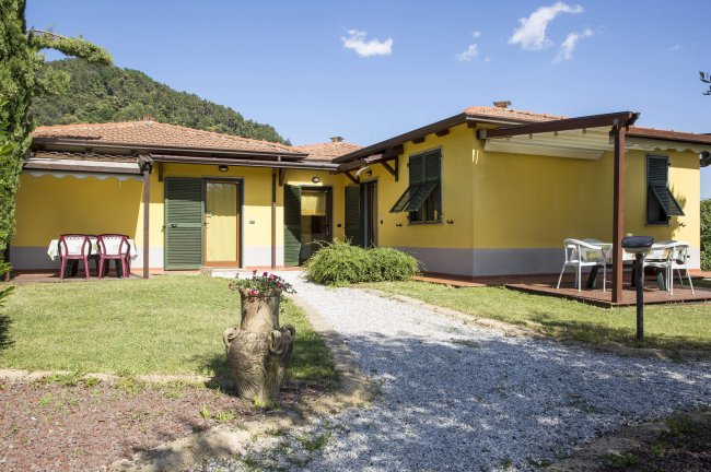 Casa gialla con giardino e vialetto ghiaioso.
