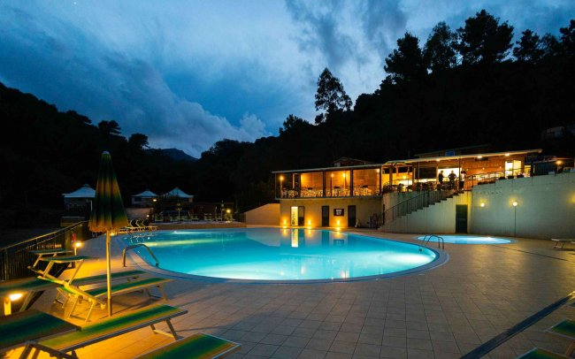 Piscina illuminata di sera con lettini.