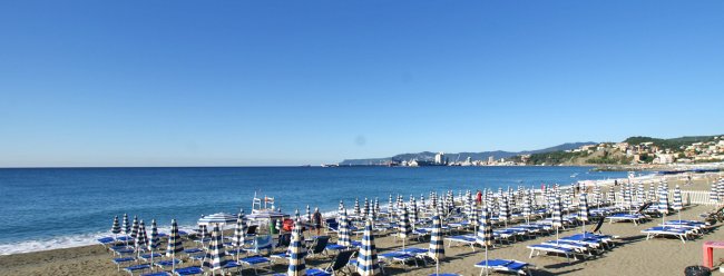 Spiaggia con file di ombrelloni e sedie a sdraio.