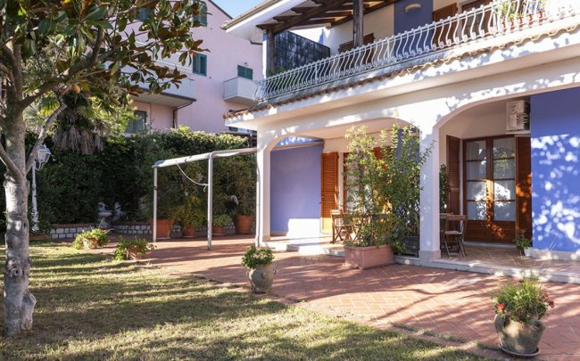 Casa con patio, giardino e piante in vasi.