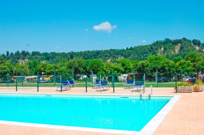 Piscina all'aperto con lettini, colline verdi.