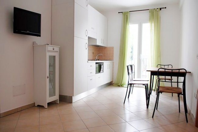 Cucina con tavolo e porte-finestre con tende verdi.