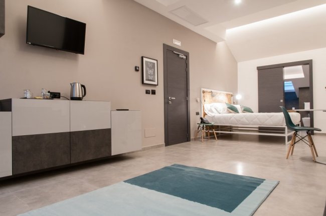 Stanza ampia con letto, TV e mobile bianco.