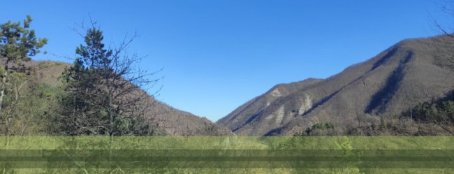 Valle con colline boscose sotto un cielo limpido.