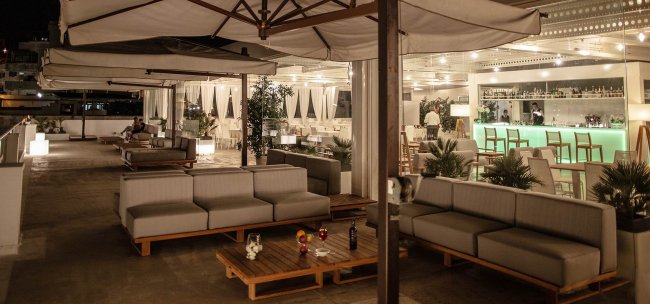 Terrazza elegante con divani e bar illuminato.