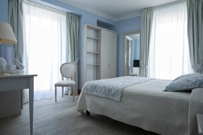 Camera con letto matrimoniale, sedia e mobili chiari.