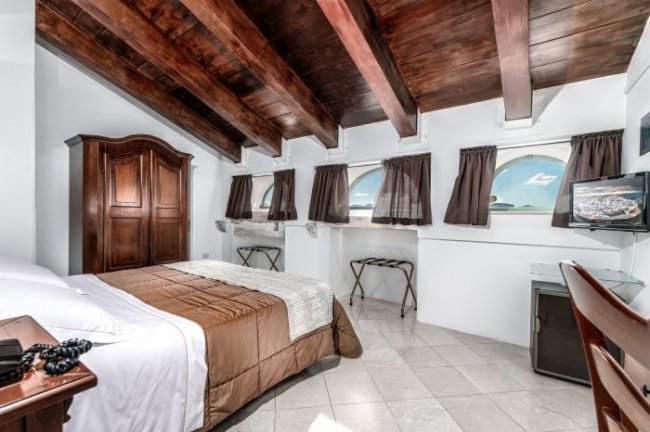 Camera con letto matrimoniale e soffitto in legno scuro.