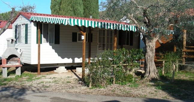 Roulotte con tenda davanti e barbecue.