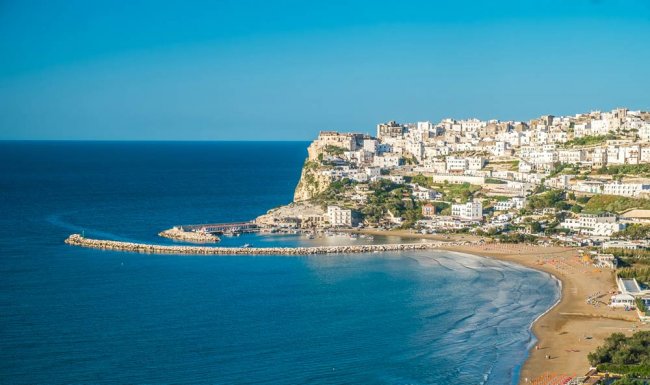 Città costiera su una scogliera con spiaggia e mare blu.