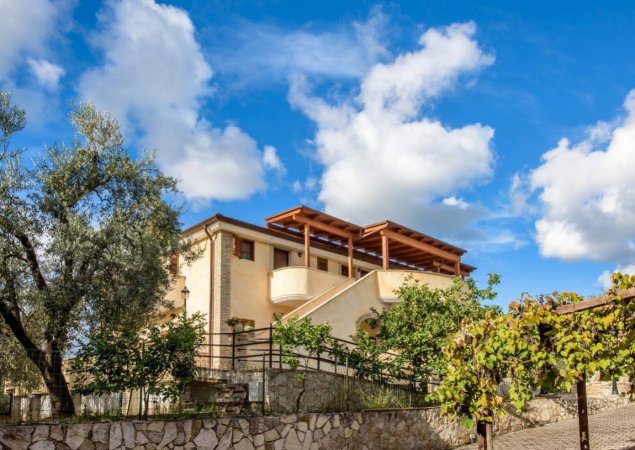 Edificio in pietra chiara con tettoia in legno.