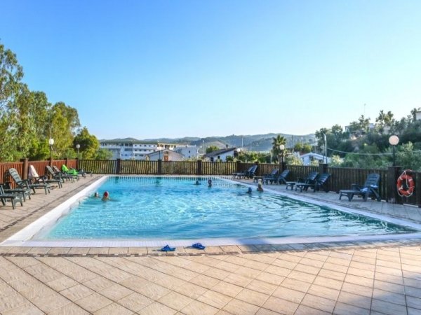 Piscina all'aperto circondata da lettini neri.