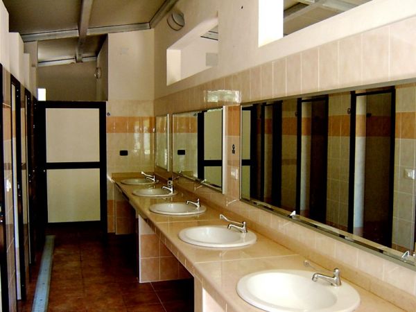 Bagni pubblici con file di lavandini e specchi.