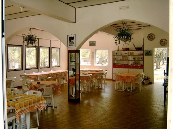 Sala da pranzo con tavoli e sedie bianchi.