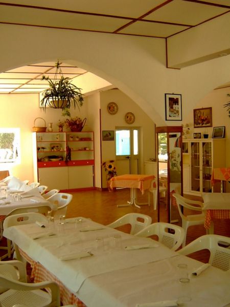 Sala da pranzo con tavoli apparecchiati.