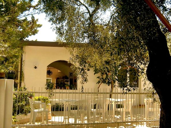 Patio con sedie bianche e vegetazione.