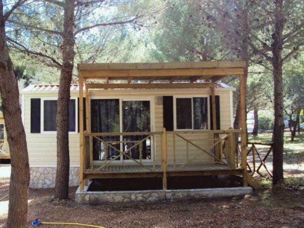 Casa mobile con veranda tra alberi.
