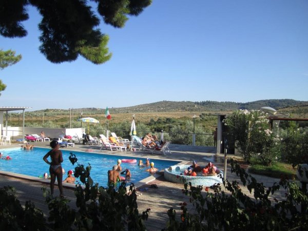 Persone che nuotano in una piscina con vista su colline.