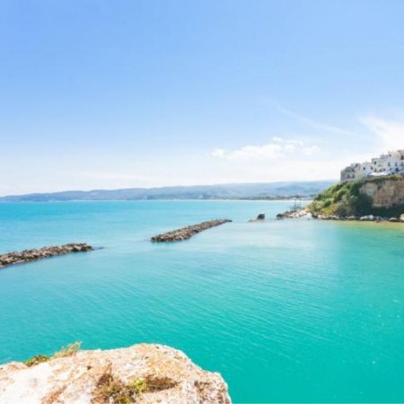 Costa rocciosa e mare turchese sotto cieli sereni.