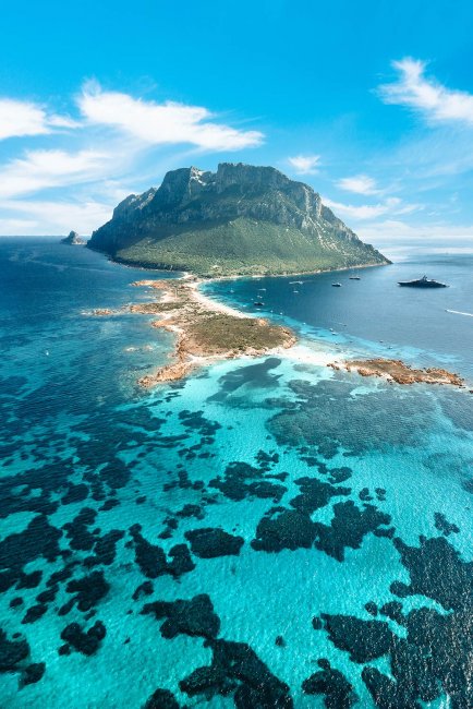 Isola con mare blu e montagne verdi.