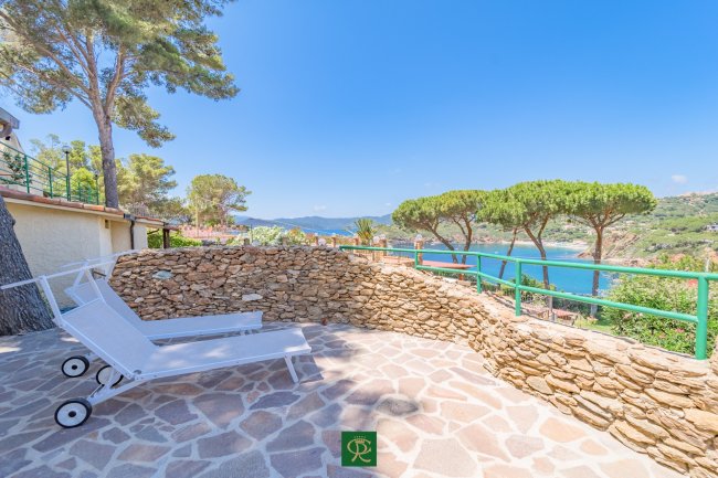 Terrazza con lettini, vista mare e pini.