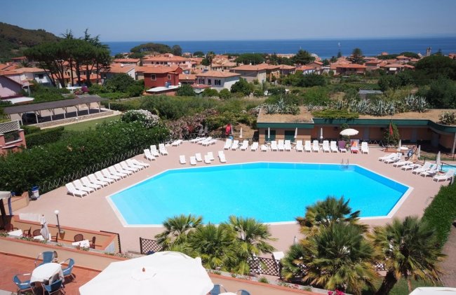 Vista dall'alto di una piscina con lettini e mare sullo sfondo.
