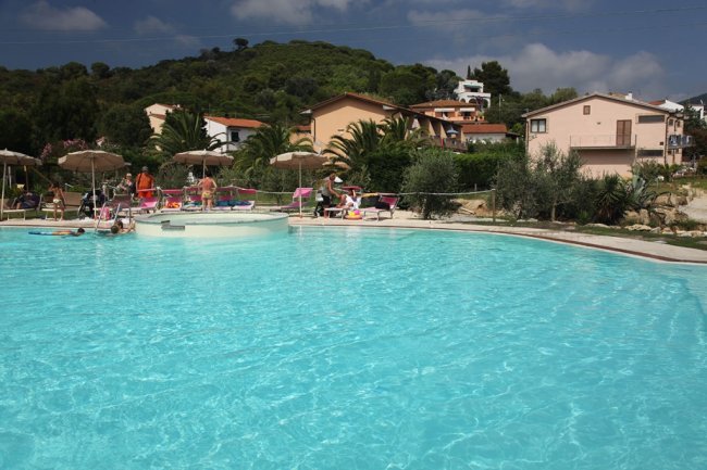 Piscina all'aperto con persone e ombrelloni.