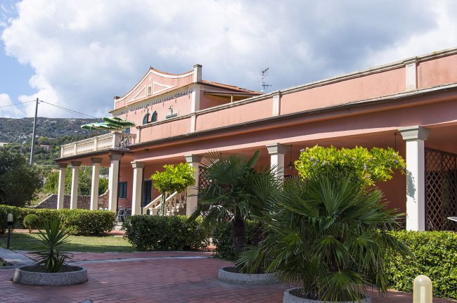 Edificio rosa con giardino e colonne.