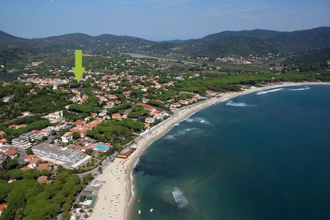 Costa panoramica con spiaggia, mare e case.