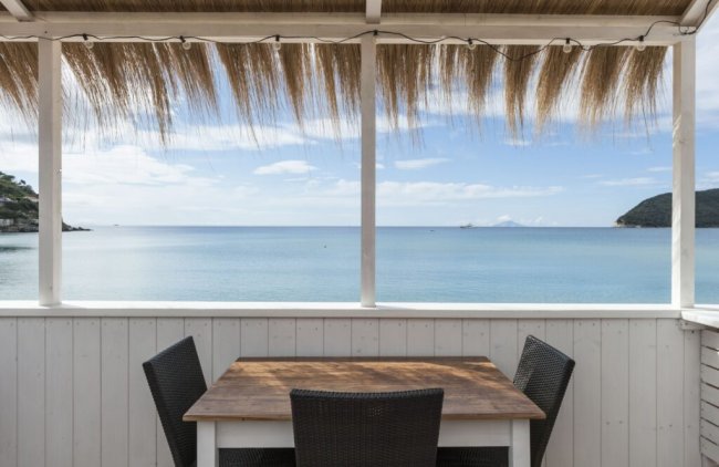 Tavolo con vista mare e tettoia in paglia.