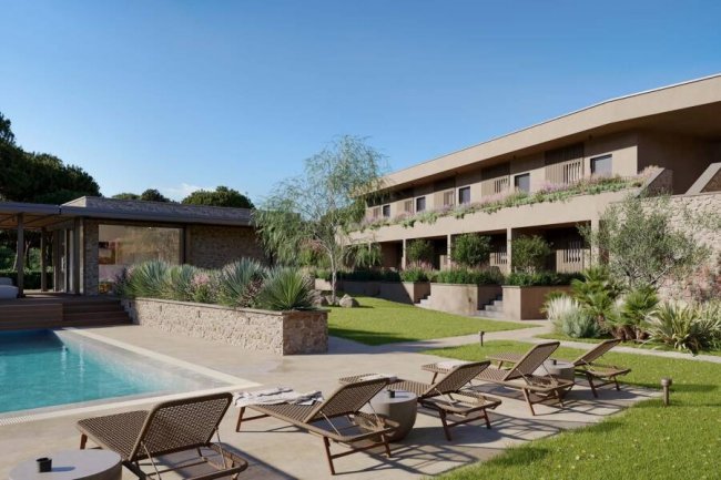Piscina con lettini e edificio moderno sullo sfondo.