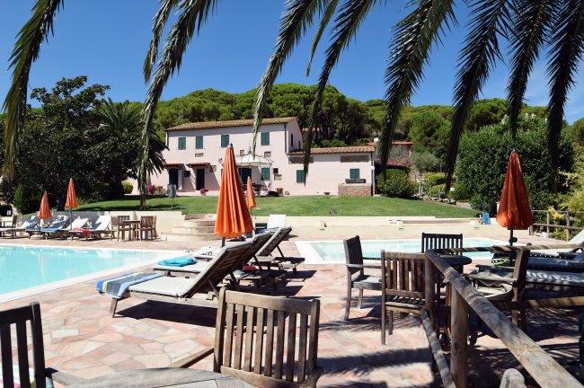 Piscina con sdraio e ombrelloni arancioni.