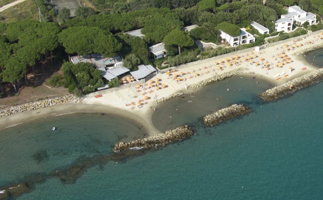 Spiaggia con lettini e ombrelloni, mare azzurro in primo piano.