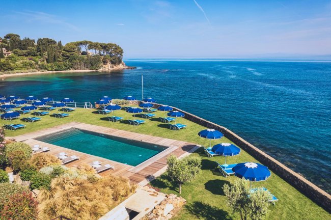 Piscina e sdraio blu vicino al mare.