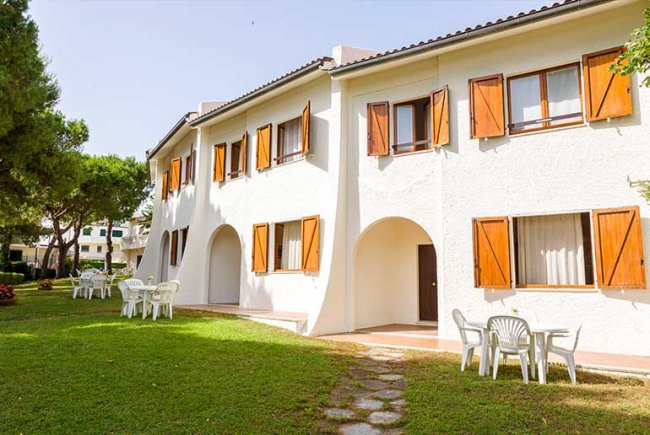 Edificio bianco con finestre marroni e giardino.