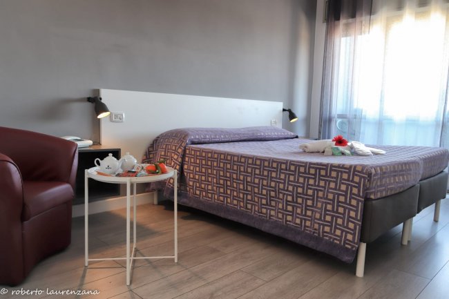 Camera d'albergo con letto matrimoniale e poltrona.