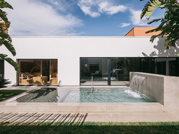 Piscina moderna con cascata vicino a un edificio bianco.