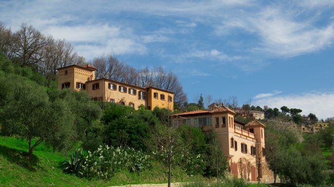 Edifici color terracotta su collina verde.