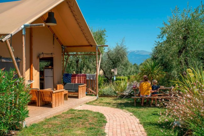 Tenda glamping con veranda e persone che mangiano.