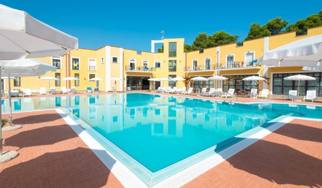 Grande piscina all'aperto circondata da ombrelloni e sedie a sdraio.