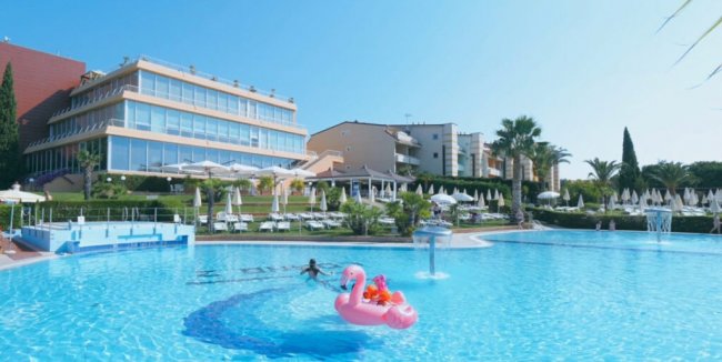 Una piscina con gonfiabile rosa e edificio sullo sfondo.