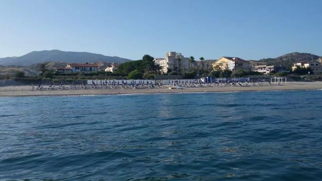 Spiaggia con ombrelloni e case sullo sfondo.