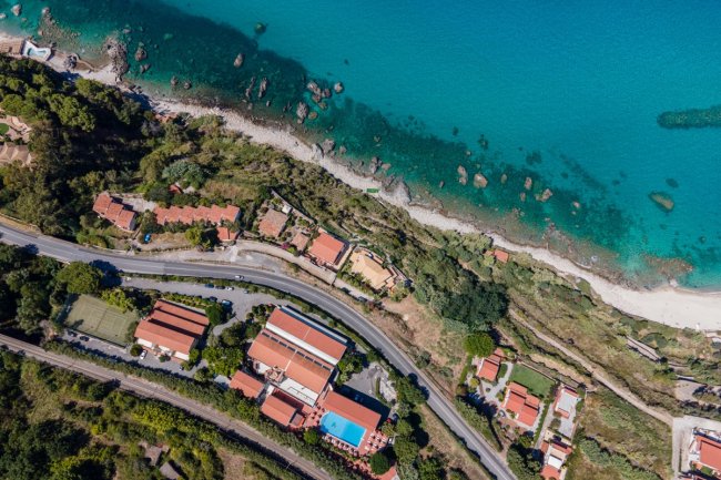 Veduta aerea di una costa con edifici e mare.